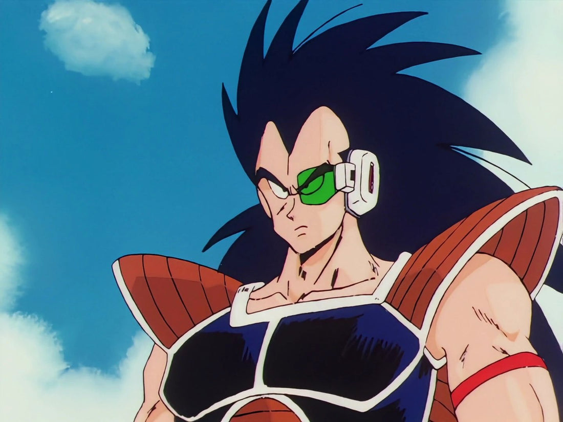 Raditz, con su larga melena negra y erizada y un scouter verde sobre el ojo izquierdo, con armadura marrón y negra y una banda roja en el brazo, sobre un fondo de cielo azul.