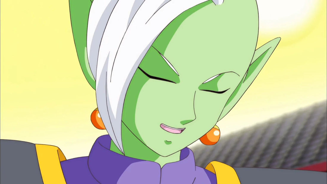 Primer plano de Zamas, de piel verde pálido, pelo blanco y pendientes naranjas, que sonríe con los ojos cerrados, con el cuello violeta bajo una túnica gris y amarilla.
